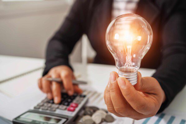 hand die een gloeilamp vasthoudt, de andere hand bedient een rekenmachine