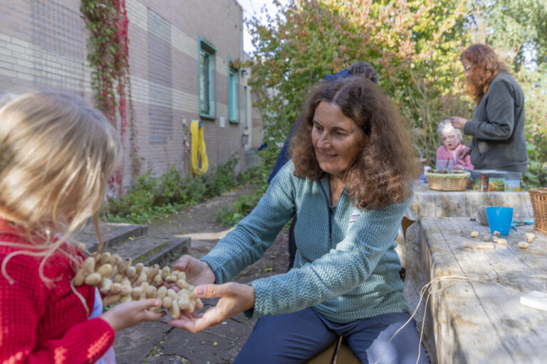 Vrijwilliger Monique van Kootwijk uit Wilnis aan het werk met een pindaketting voor een meisje. 