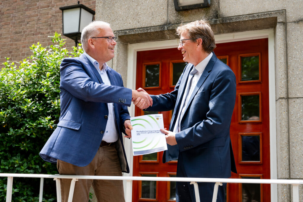 Portefeuillehouder Wouter Catsburg en wethouder van Gemeente Lopik, Jan Vente met mandaatbesluit in hun hand schudden elkaar de hand. Ze luiden een nieuwe fase in waarbij de gemeente Lopik de uitvoering van bouw- en slooptaken overdraagt aan ons.